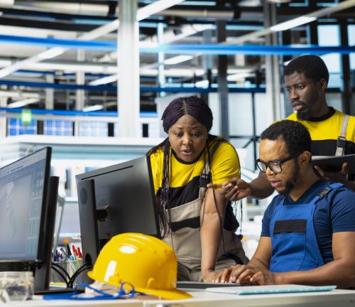 Black team of manufacturing plant employees fixing errors and debugging technical issues, working together in the assembly line of solar panels at the industrial factory. Renewable energy.